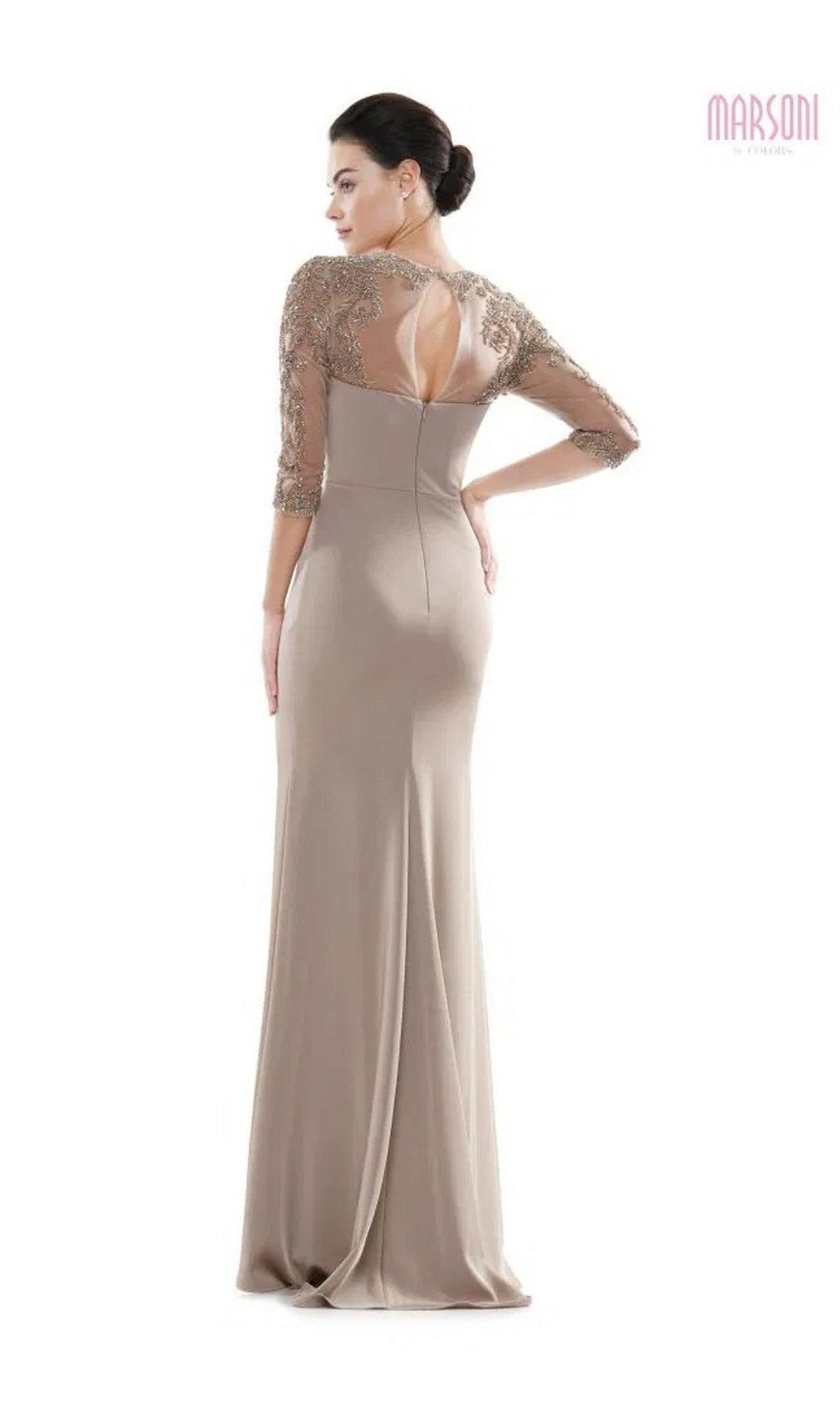 A woman stands facing away, wearing the Marsoni MV1070 long formal dress with a floor-length taupe column skirt, lace detailing, and beaded appliques on the upper back and sleeves.
